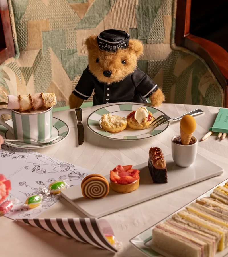 Claridge’s teddy bear at children’s afternoon tea table with scones, pastries, sandwiches and marshmallow hot chocolate.