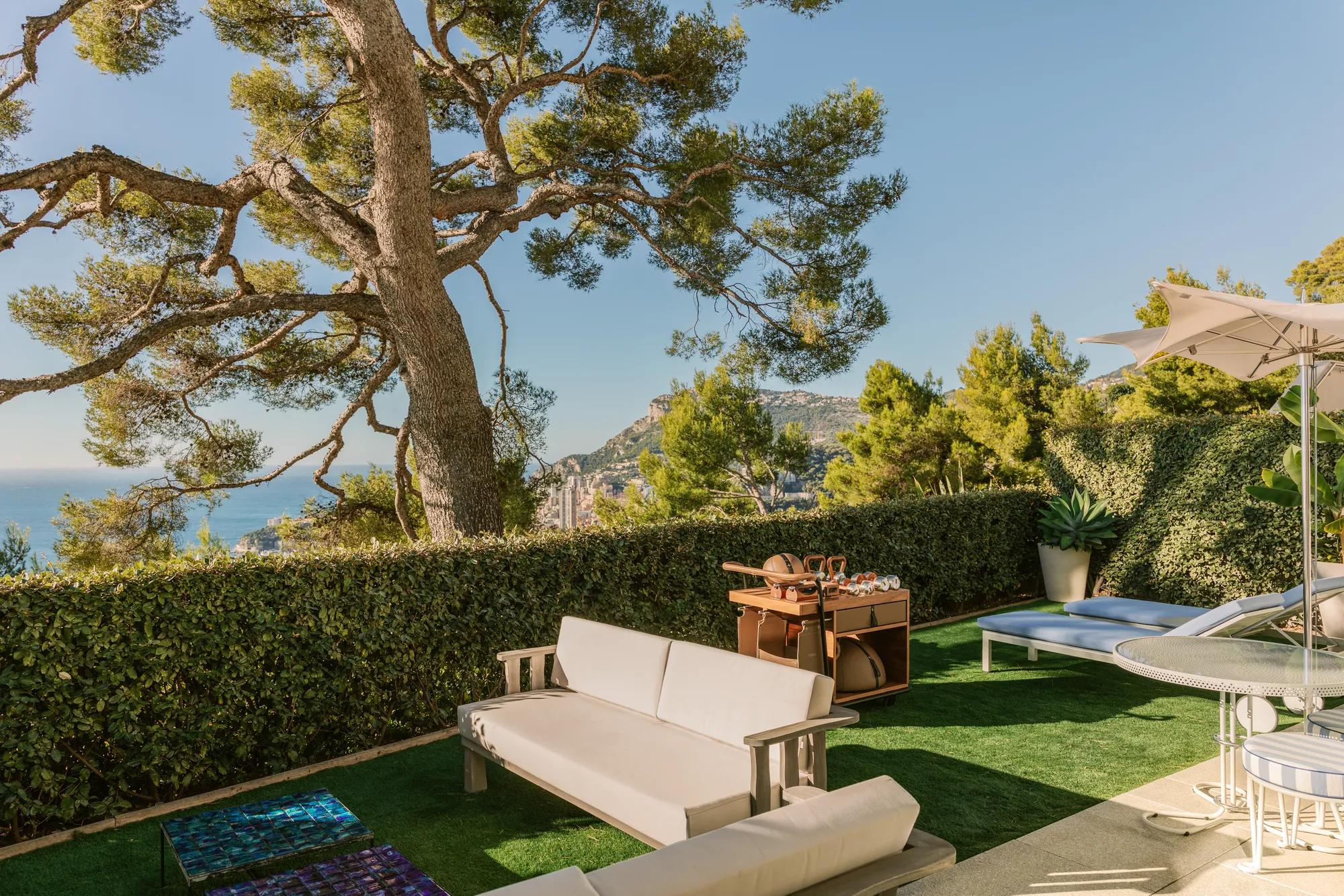 Private garden terrace with outdoor seating, sun loungers and sea and hillside views.