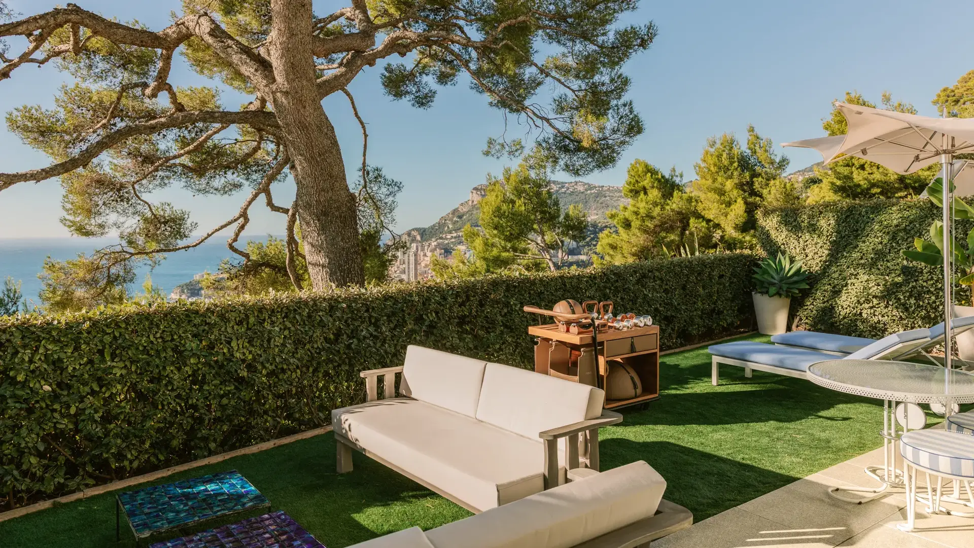 Private garden terrace with outdoor seating, sun loungers and sea and hillside views.
