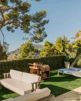 Private garden terrace with outdoor seating, sun loungers and sea and hillside views.