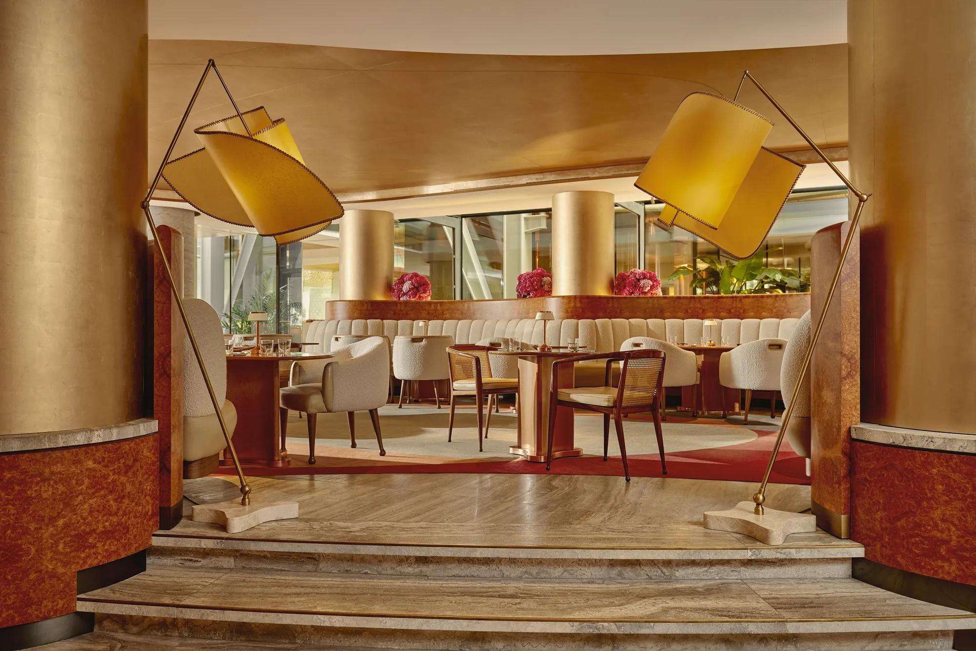 Elegant cafe interior with soft cream chairs, golden columns, and modern curved lighting.