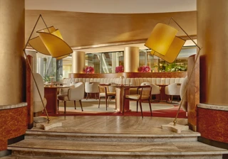 Elegant cafe interior with soft cream chairs, golden columns, and modern curved lighting.