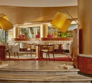 Elegant cafe interior with soft cream chairs, golden columns, and modern curved lighting.