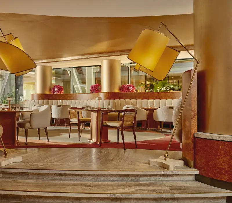 Elegant cafe interior with soft cream chairs, golden columns, and modern curved lighting.