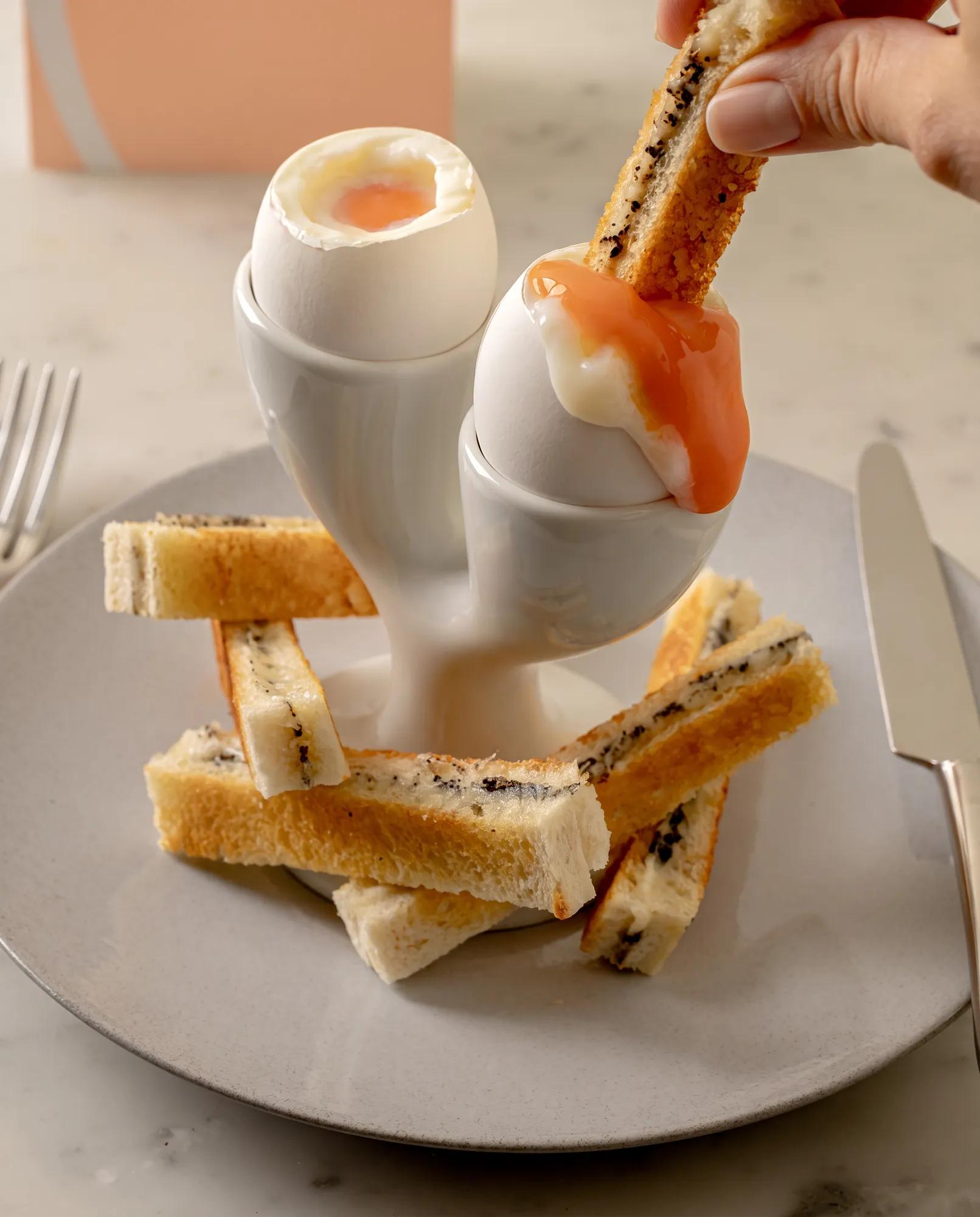 Soft-boiled eggs with toast soldiers served in a sculptural egg holder.