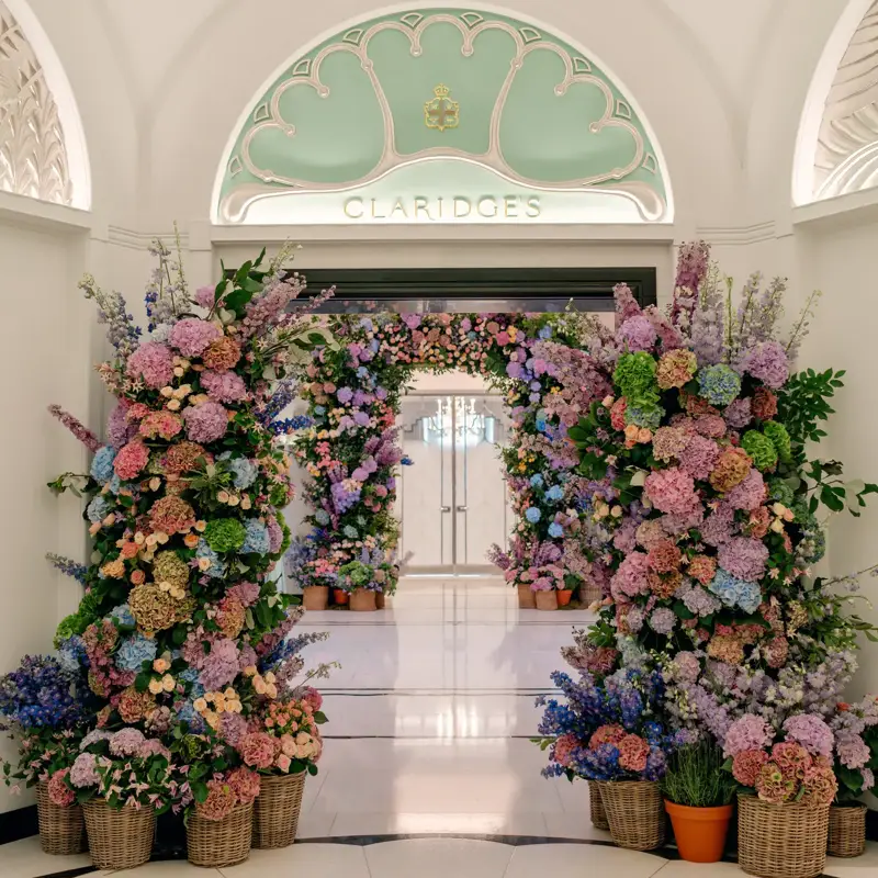 Floral arch of pink, purple and blue blooms frames the Claridge’s entrance beneath an arched ceiling.