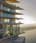 Modern cliffside hotel with glass balconies overlooking the sea at sunset.
