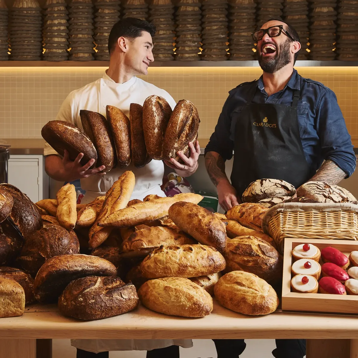 Claridge’s Bakery chefs Richard Hart and Frédéric Doncel‑Latorre standing together in the bakery, showcasing their craft in an elegant, warmly lit setting.