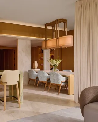 Elegant bar area with green onyx counter, high chairs, and open shelving leading to dining space with six upholstered chairs.