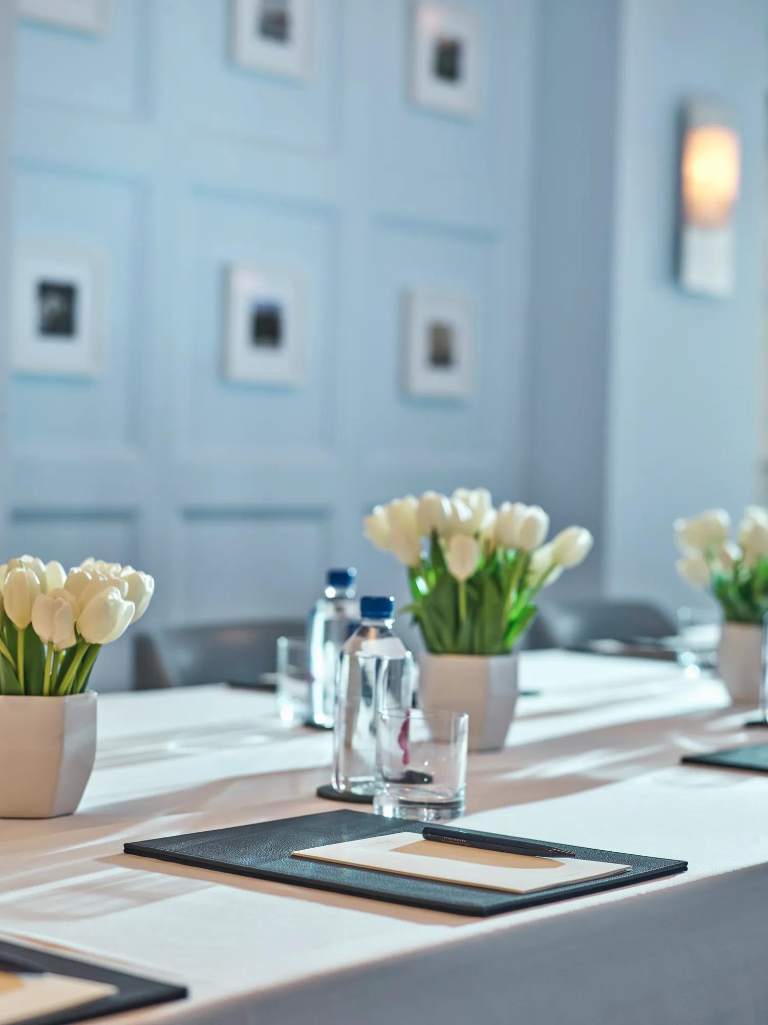 Close-up of Canon Room meeting table with tulips, notepads, and water bottles.