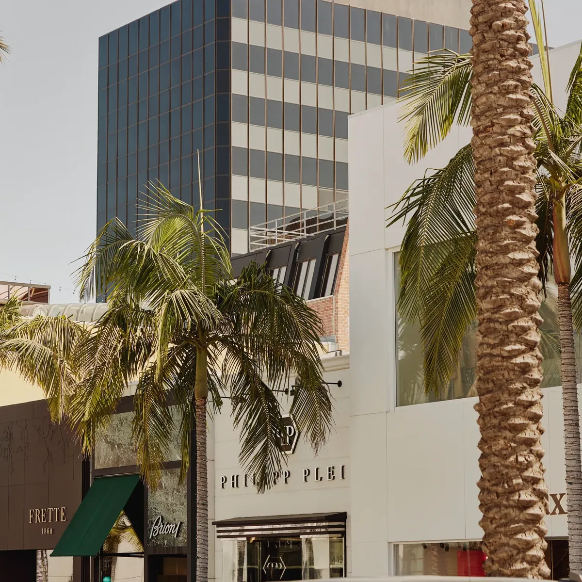 Rodeo Drive boutiques—Frette, Brioni, and Philipp Plein—set among palms and mixed modern architecture.