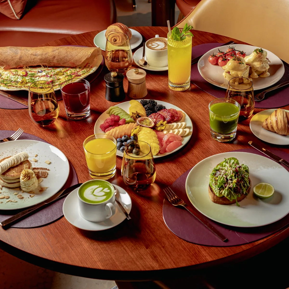 Breakfast wooden table including several plates of sweet and savoury plates.