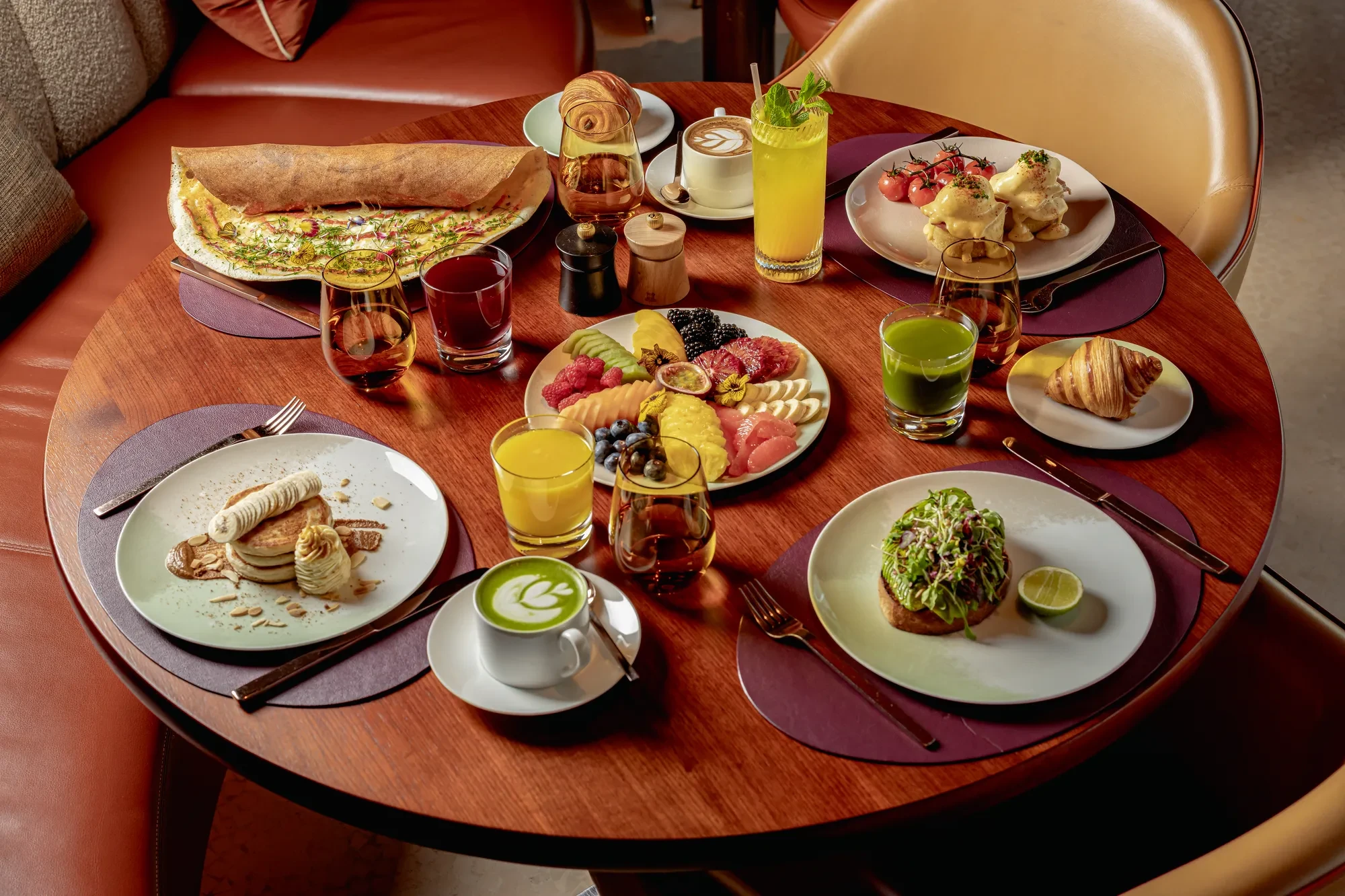 Breakfast wooden table including several plates of sweet and savoury plates.