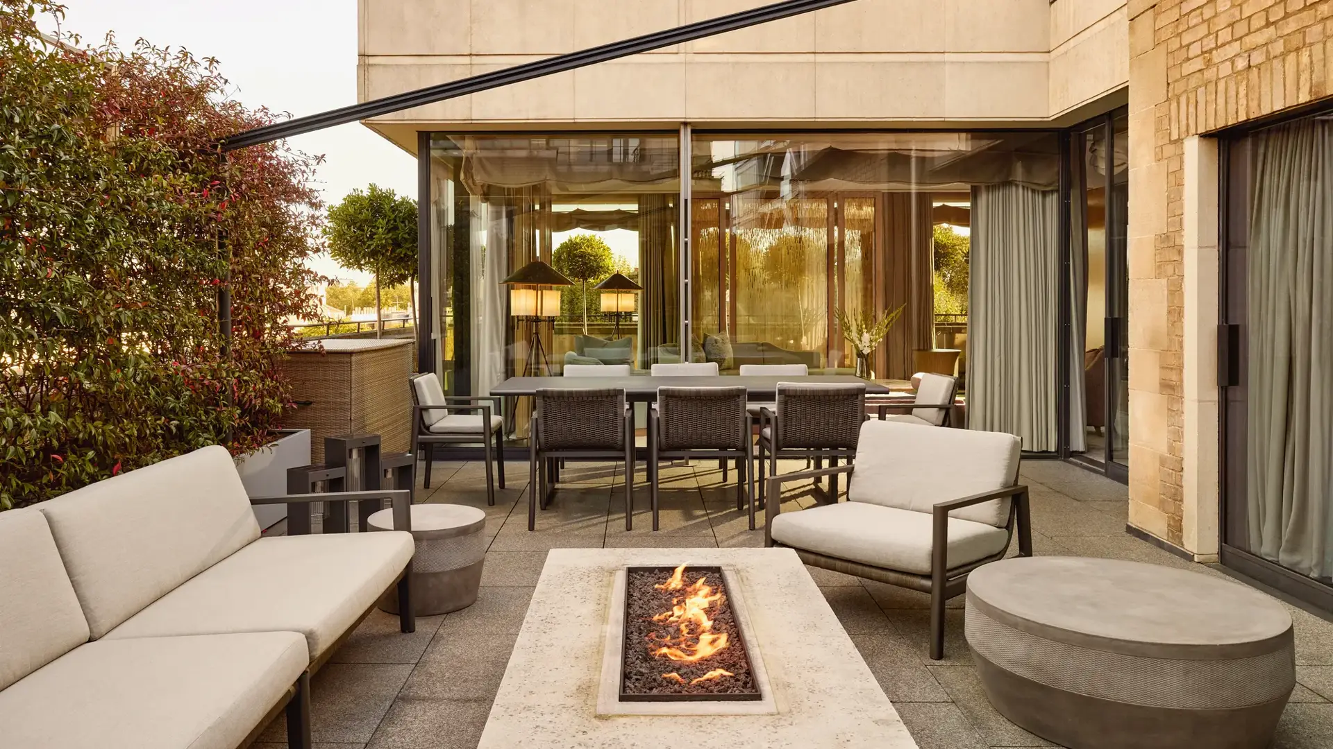 Penthouse terrace with modern fire pit, outdoor seating, and dining area beside large glass doors