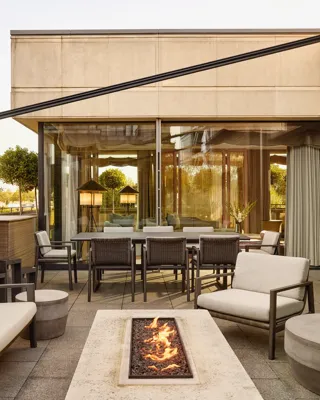 Penthouse terrace with modern fire pit, outdoor seating, and dining area beside large glass doors
