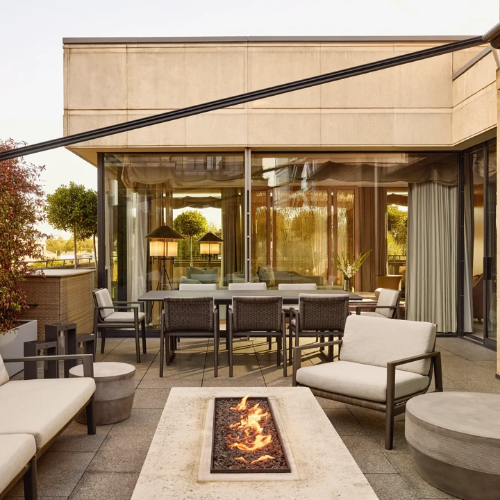 Penthouse terrace with modern fire pit, outdoor seating, and dining area beside large glass doors
