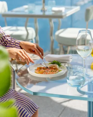 Personne dégustant des fruits de mer, tenant une fourchette au‑dessus d’une assiette de coquillages frais.