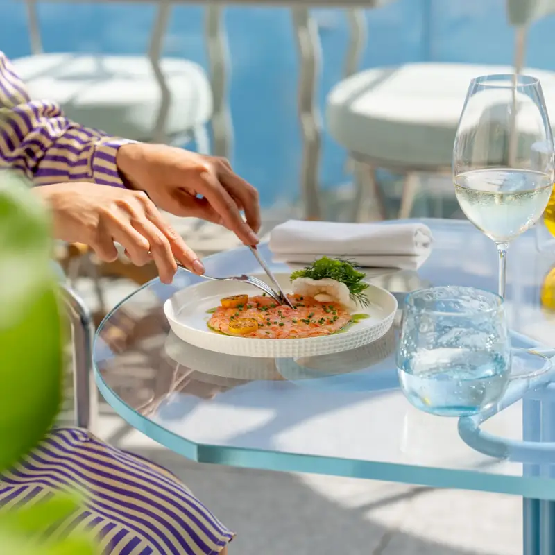 Personne dégustant des fruits de mer, tenant une fourchette au‑dessus d’une assiette de coquillages frais.