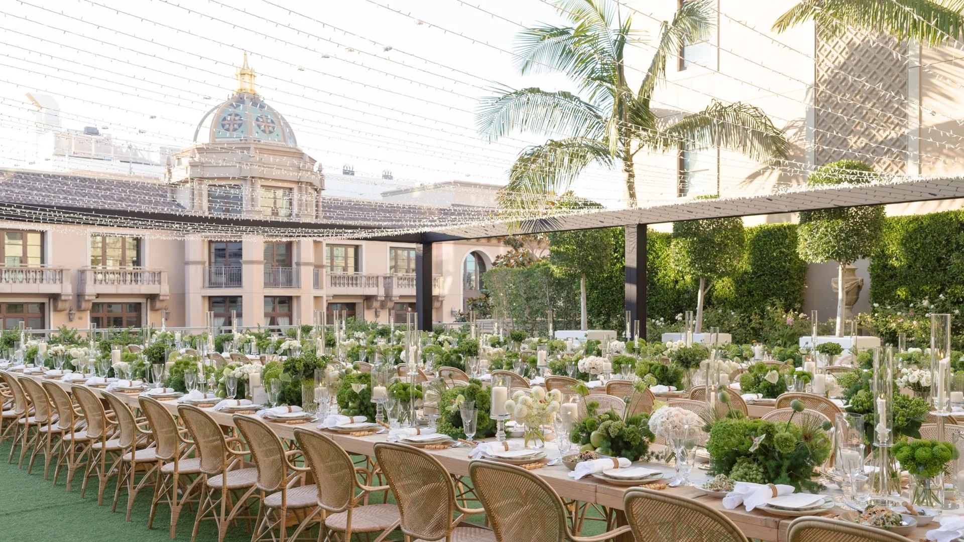 Rows of long banquet tables with green and white decor on a Beverly Hills garden terrace.
