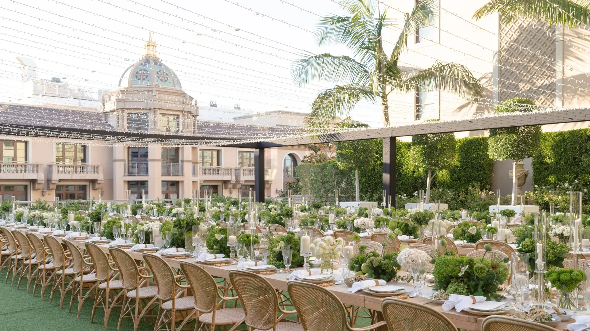Rows of long banquet tables with green and white decor on a Beverly Hills garden terrace.