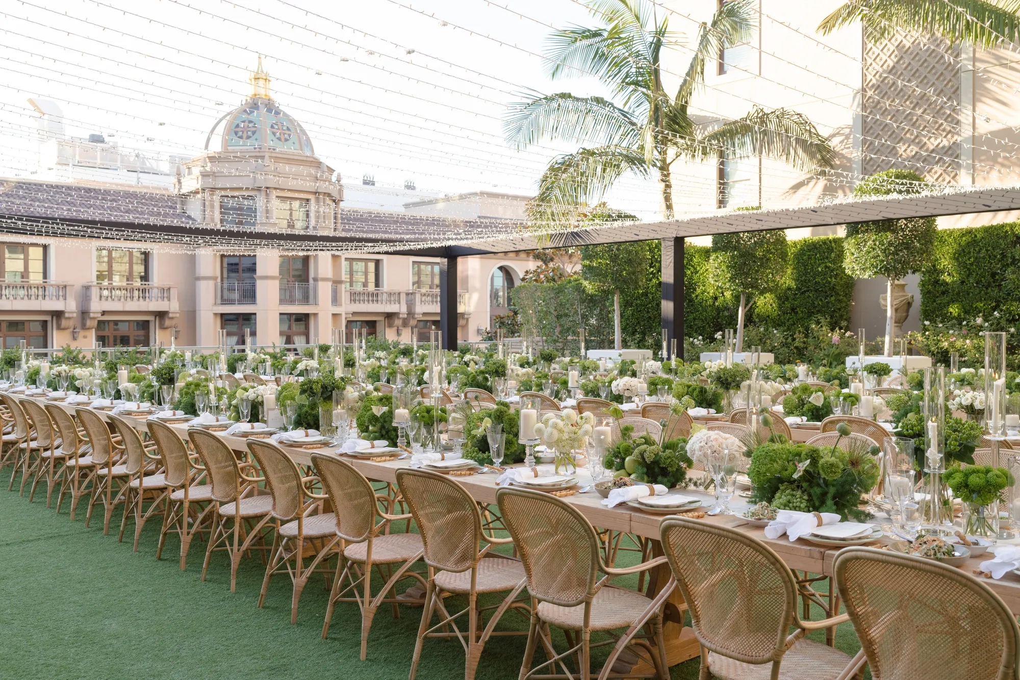 Rows of long banquet tables with green and white decor on a Beverly Hills garden terrace.