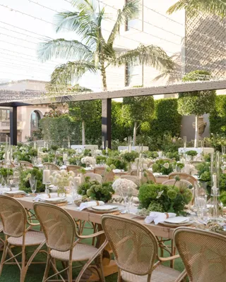 Rows of long banquet tables with green and white decor on a Beverly Hills garden terrace.