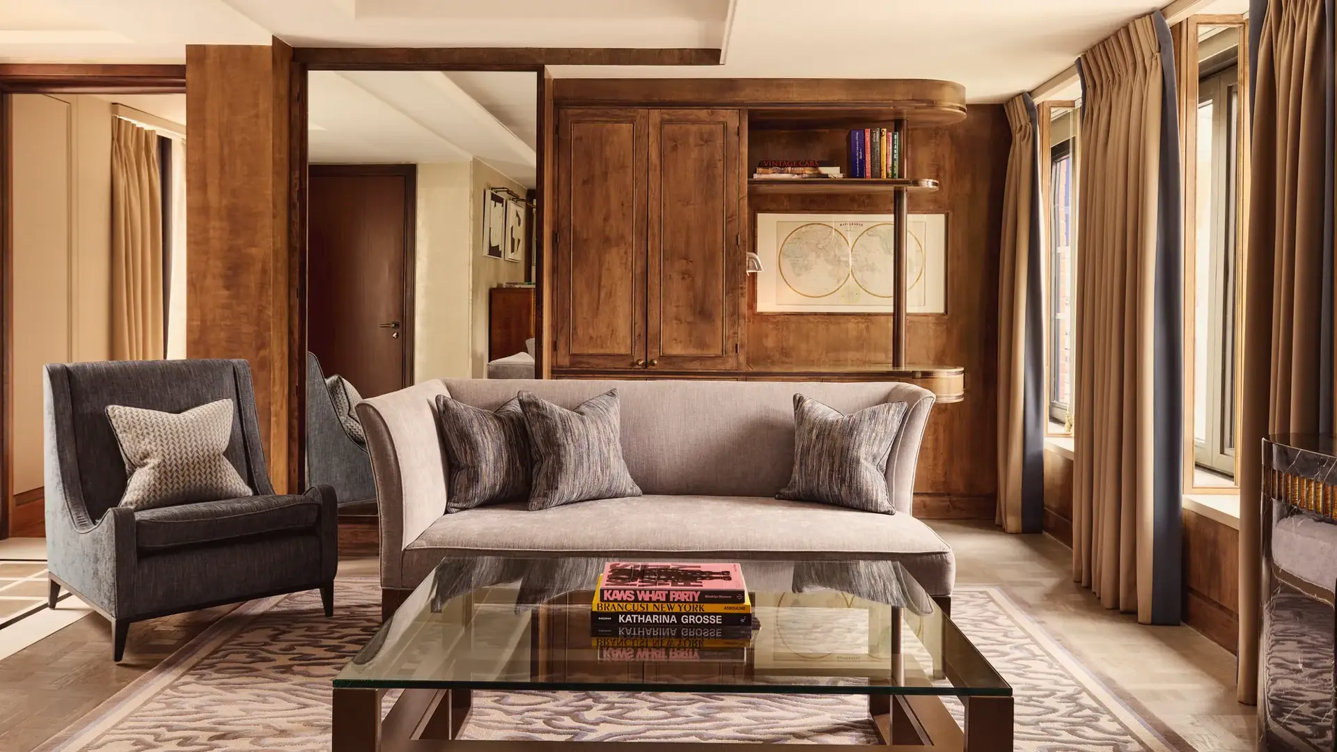 Elegant suite living room with grey sofa, armchair, wood panelling and large windows.