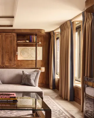 Elegant suite living room with grey sofa, armchair, wood panelling and large windows.