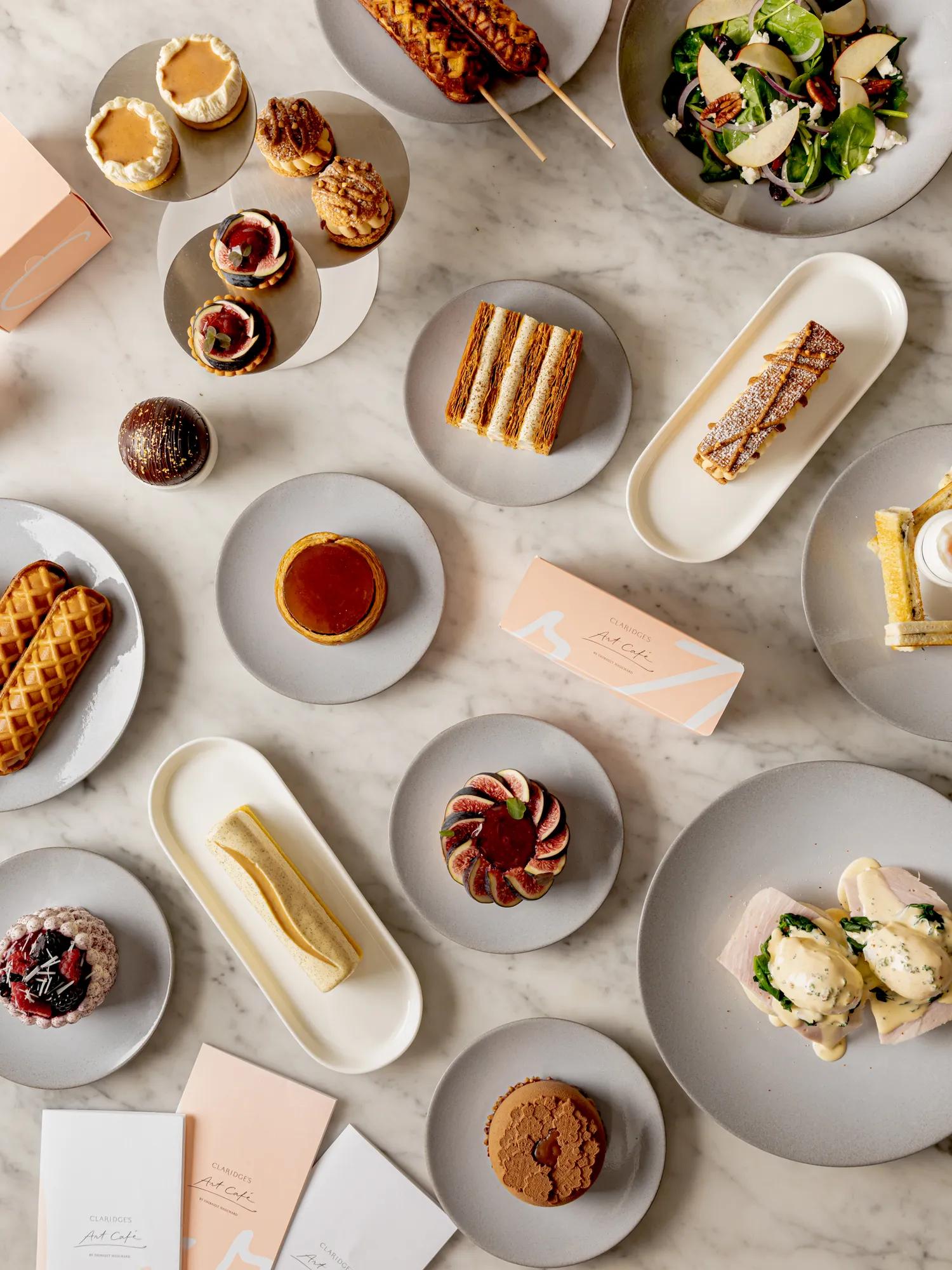 Overhead view of signature dishes and pastries from Art Café by Thibault Hauchard displayed on a marble table.