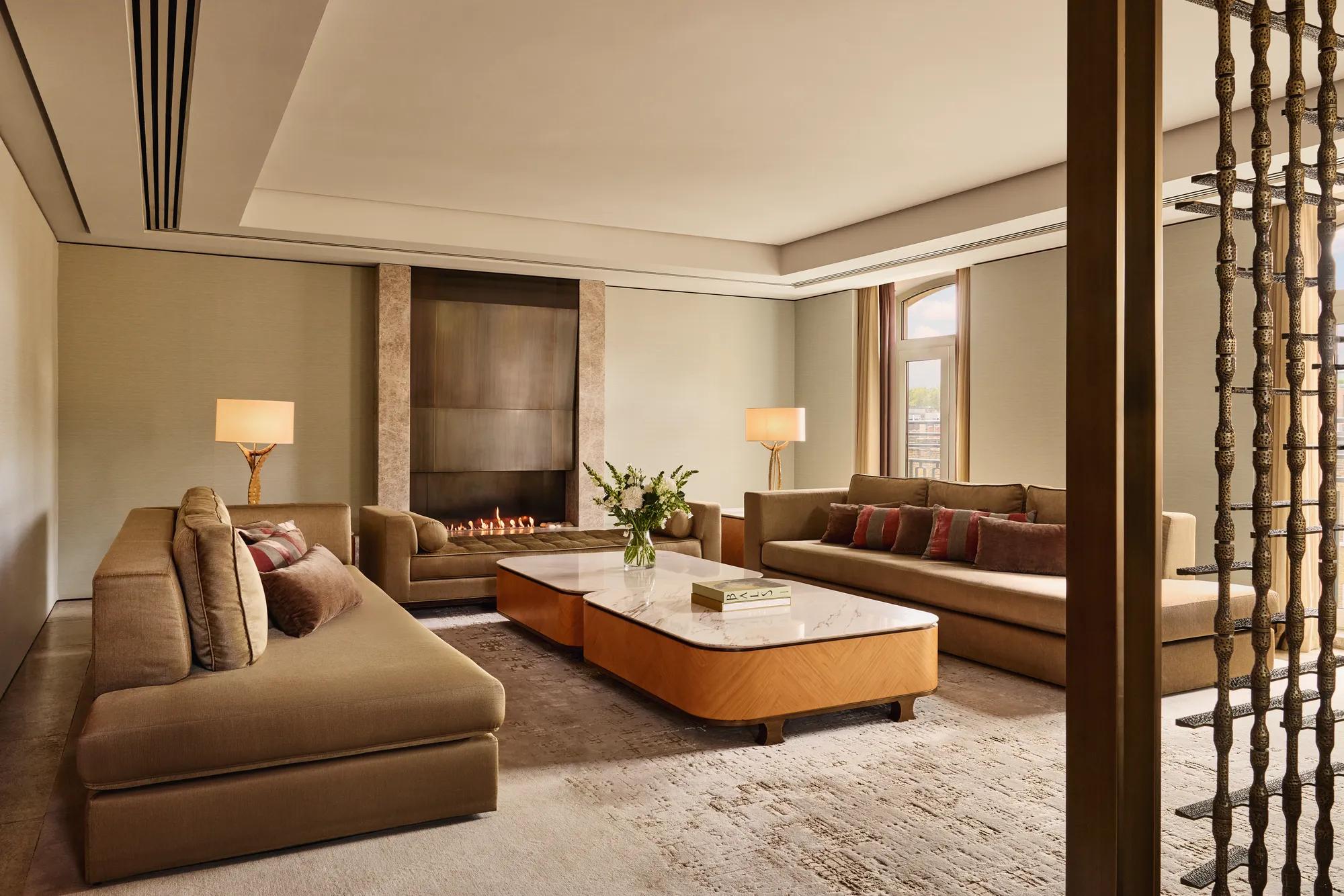 Spacious Opus Suite living room with sofas, marble tables, and a modern fireplace