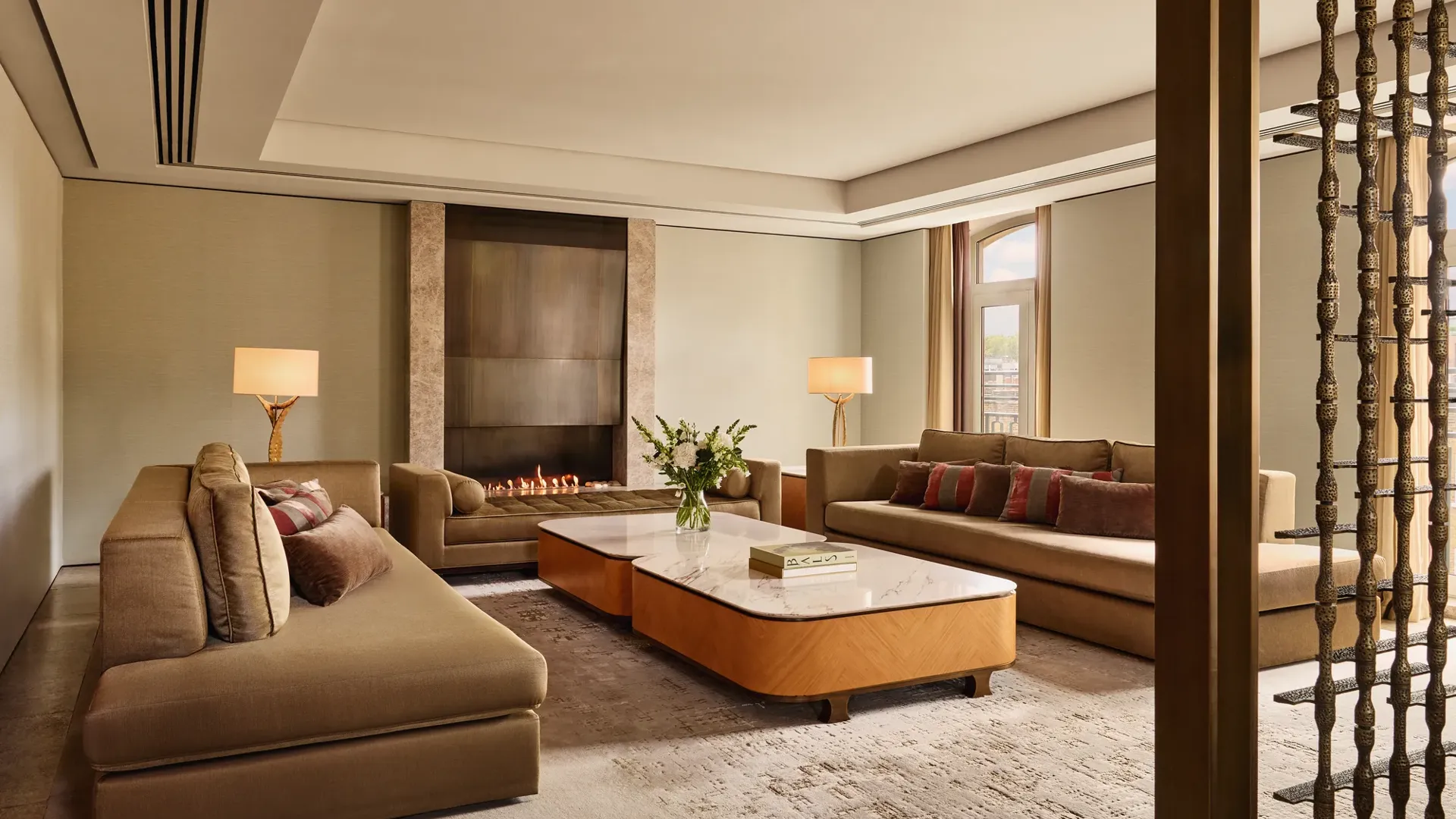Spacious Opus Suite living room with sofas, marble tables, and a modern fireplace