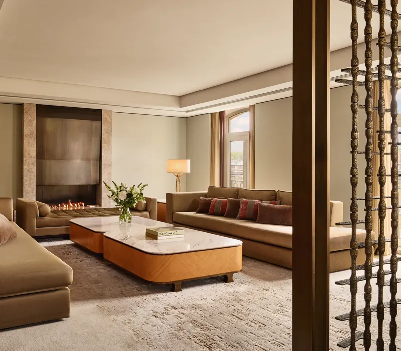 Spacious Opus Suite living room with sofas, marble tables, and a modern fireplace