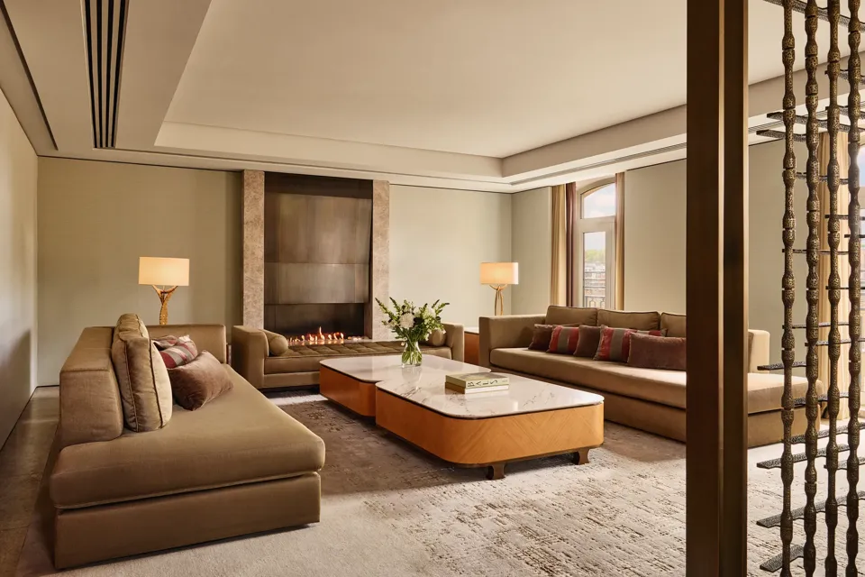 Spacious Opus Suite living room with sofas, marble tables, and a modern fireplace