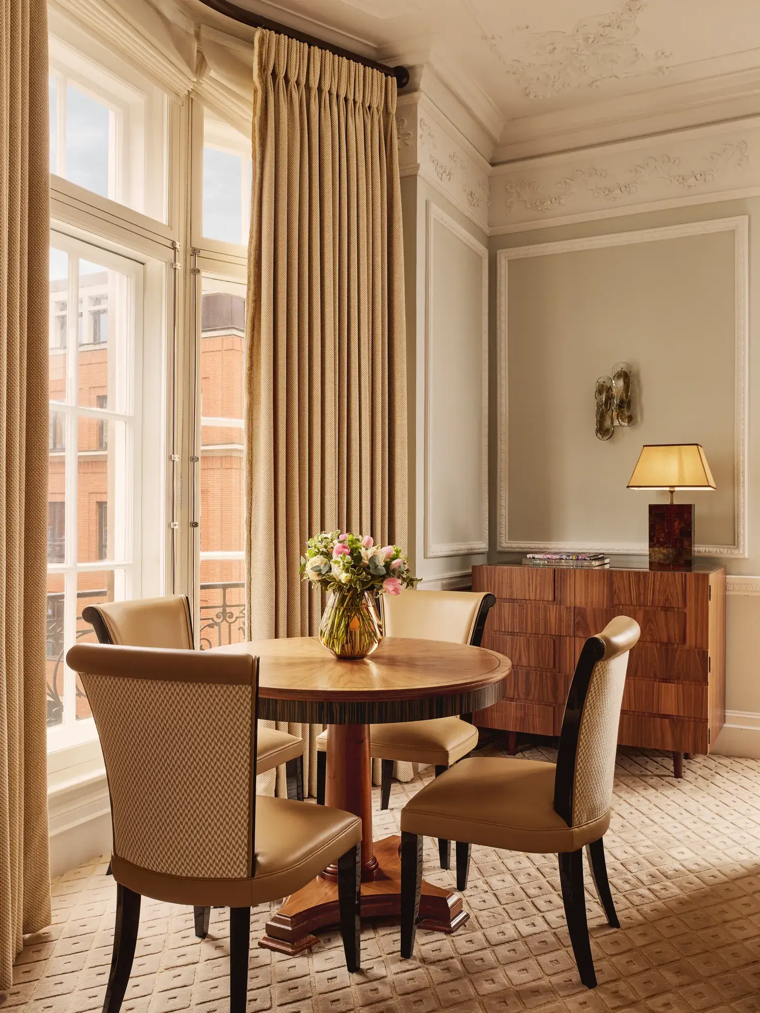 A spacious corner suite at Claridge’s featuring elegant contemporary décor, large windows with city views, and refined, luxurious furnishings
