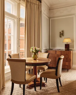 A spacious corner suite at Claridge’s featuring elegant contemporary décor, large windows with city views, and refined, luxurious furnishings