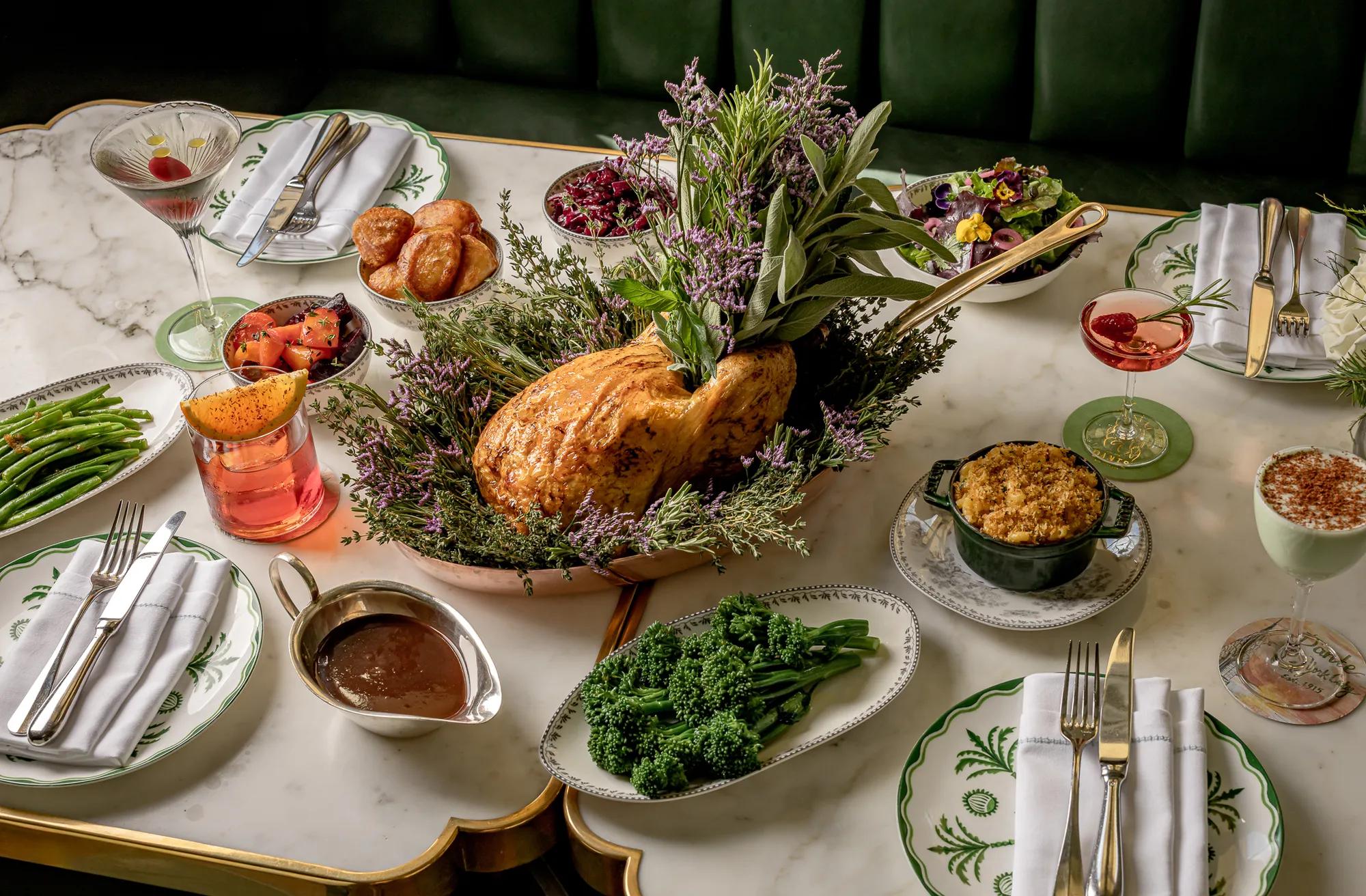 Roast turkey presented with seasonal vegetables, stuffing, gravy and cocktails on an elegantly set dining table.