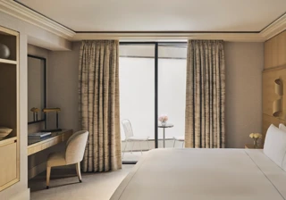 Serene bedroom with desk, king bed, and private courtyard terrace with two white chairs and a marble table.