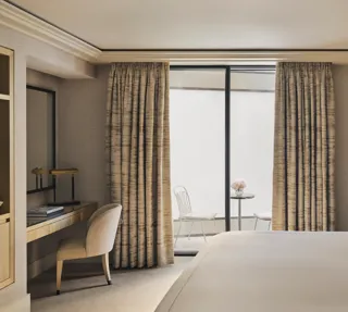 Serene bedroom with desk, king bed, and private courtyard terrace with two white chairs and a marble table.
