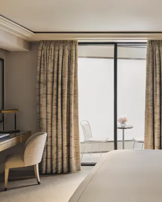 Serene bedroom with desk, king bed, and private courtyard terrace with two white chairs and a marble table.