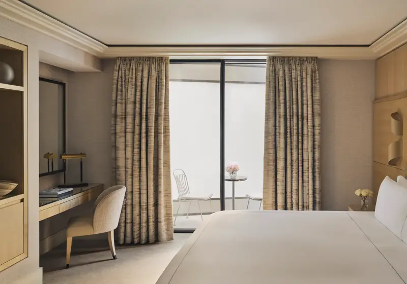 Serene bedroom with desk, king bed, and private courtyard terrace with two white chairs and a marble table.