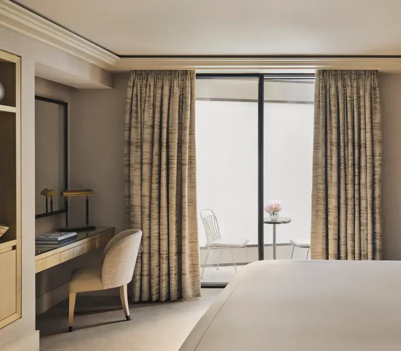 Serene bedroom with desk, king bed, and private courtyard terrace with two white chairs and a marble table.