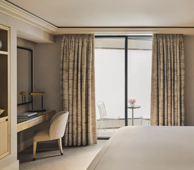 Serene bedroom with desk, king bed, and private courtyard terrace with two white chairs and a marble table.