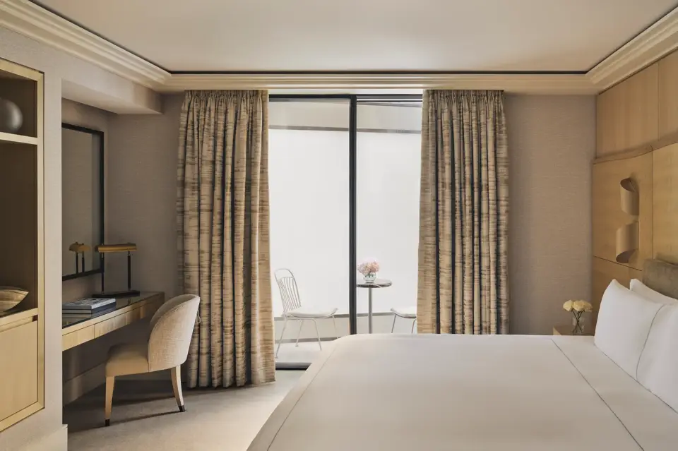 Serene bedroom with desk, king bed, and private courtyard terrace with two white chairs and a marble table.