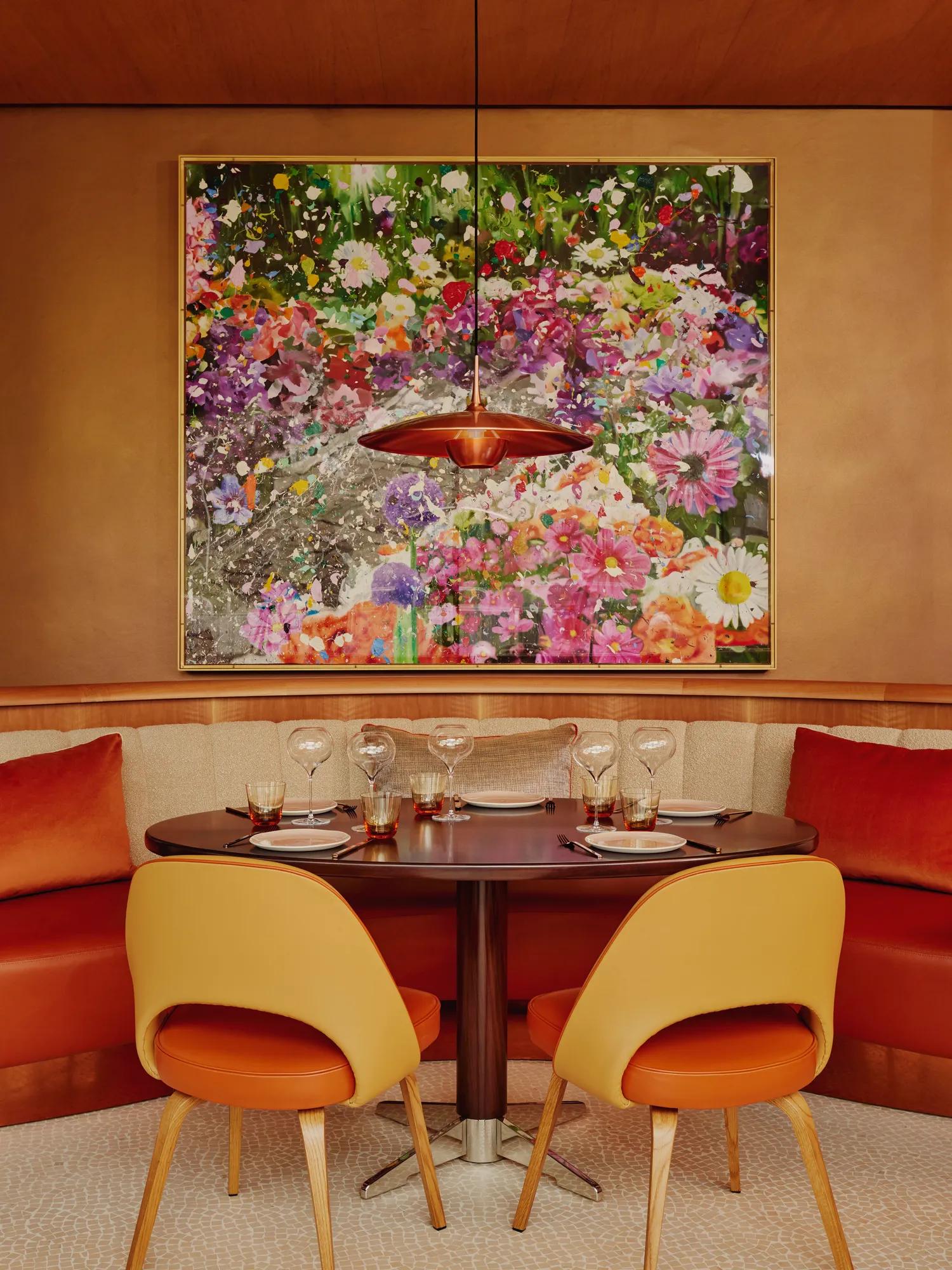 Table for four set beneath a floral artwork in a vibrant, modern restaurant.