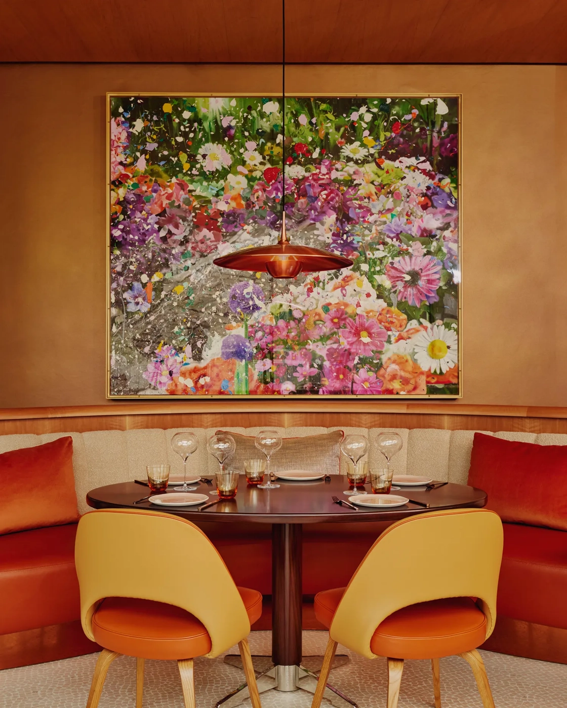 Table for four set beneath a floral artwork in a vibrant, modern restaurant.