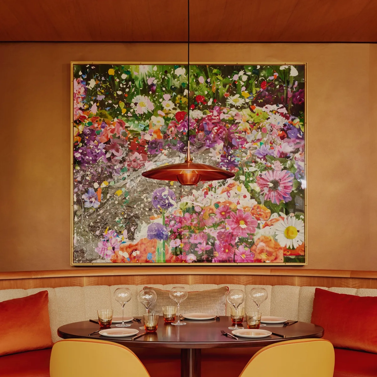 Table for four set beneath a floral artwork in a vibrant, modern restaurant.