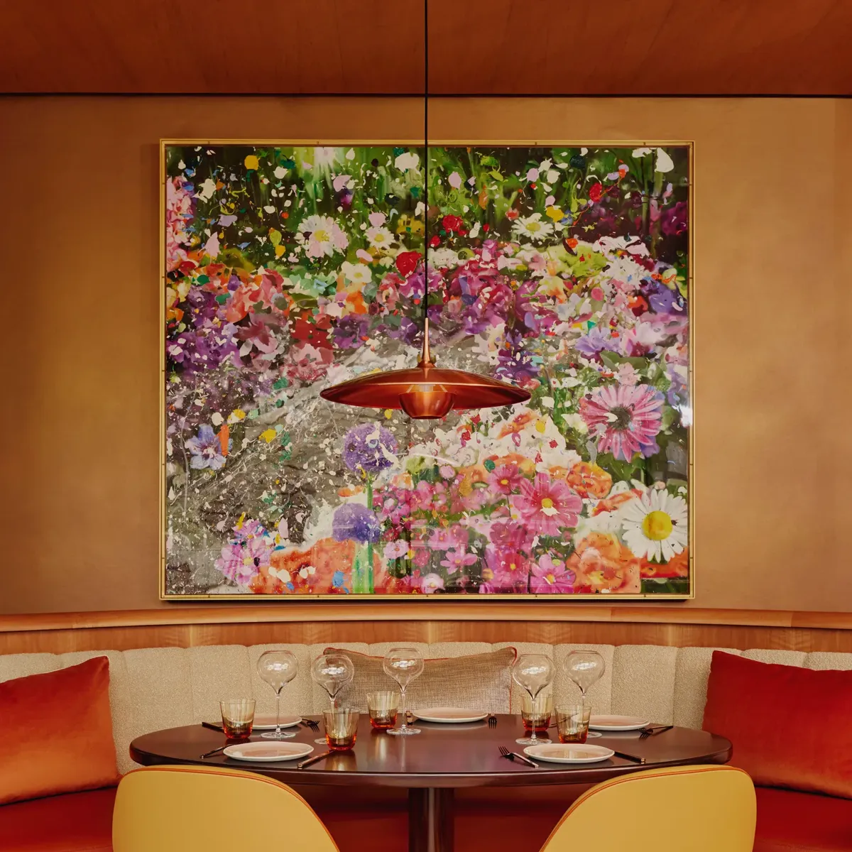 Table for four set beneath a floral artwork in a vibrant, modern restaurant.