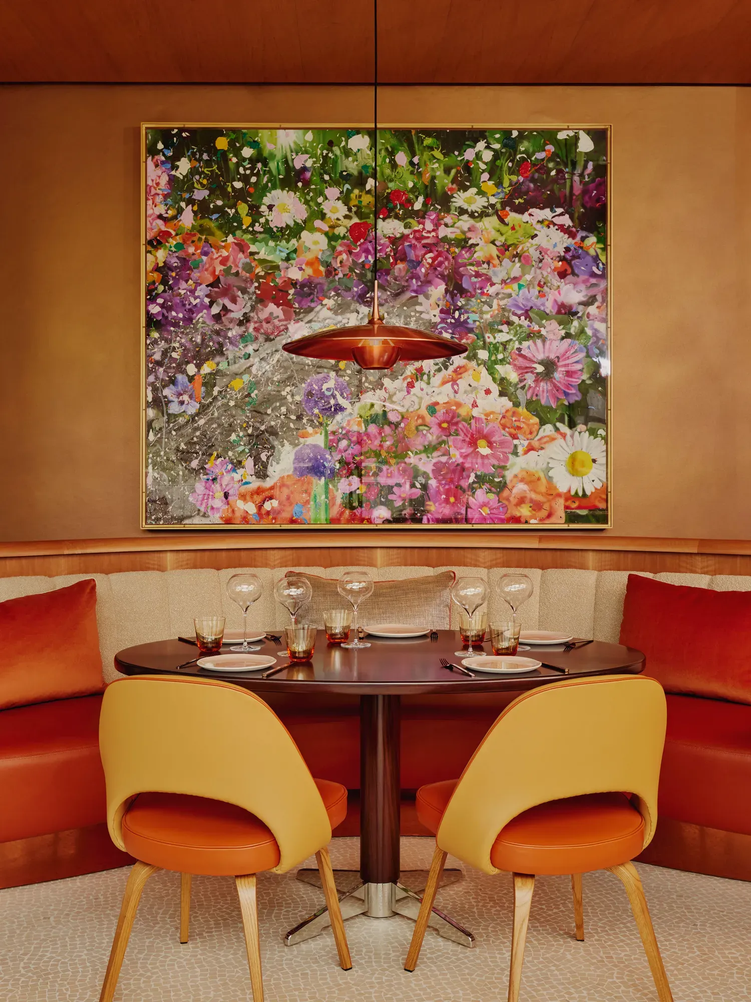 Table for four set beneath a floral artwork in a vibrant, modern restaurant.