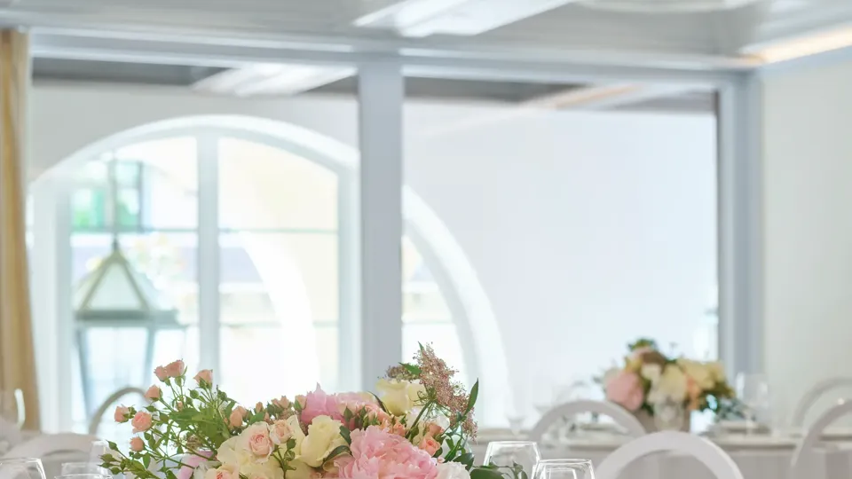 Beverly conference room round tables with blush floral centerpieces and crystal glassware.