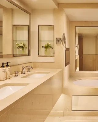 Marble bathroom with double sinks, built-in bathtub, large mirror, and separate bidet.